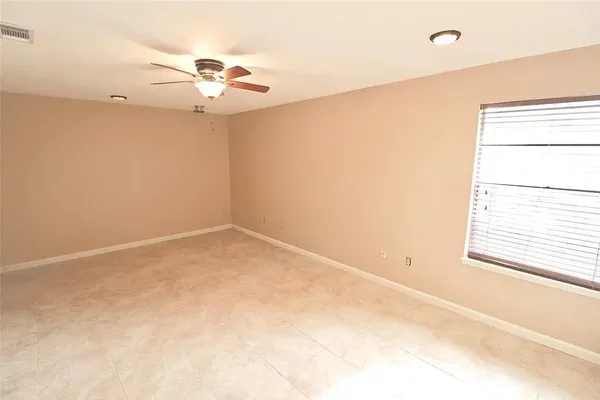 an empty room with a fan and a window