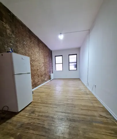 a view of empty room with window and refrigerator