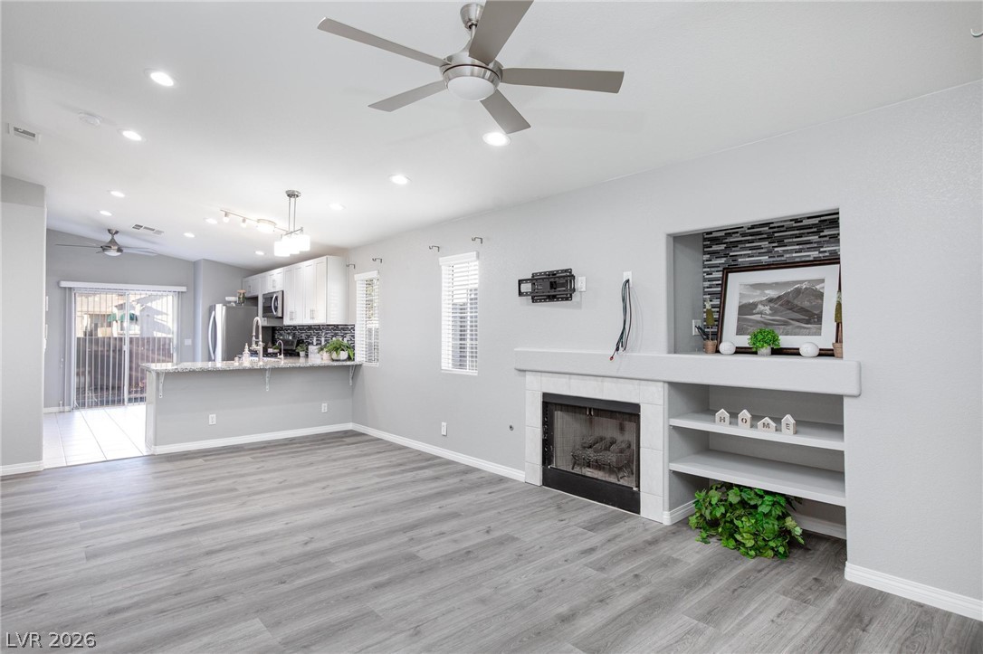 2254 Ramsgate Drive Henderson, NV 89074 - Photo 4 of 43 An open concept living area features sleek flooring, a modern fireplace, and a connected kitchen with a breakfast bar.