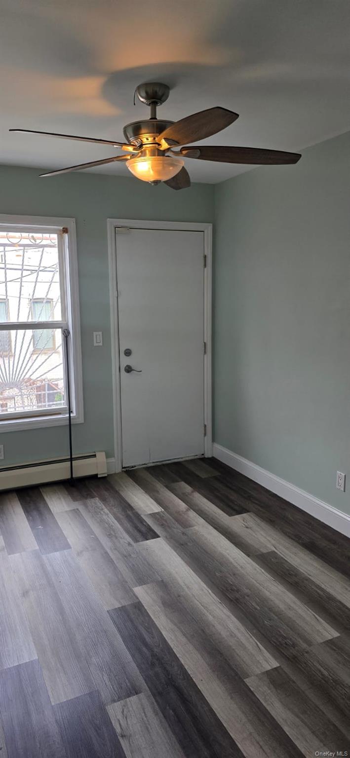 Entryway with ceiling fan, a baseboard radiator, and wood finished floors