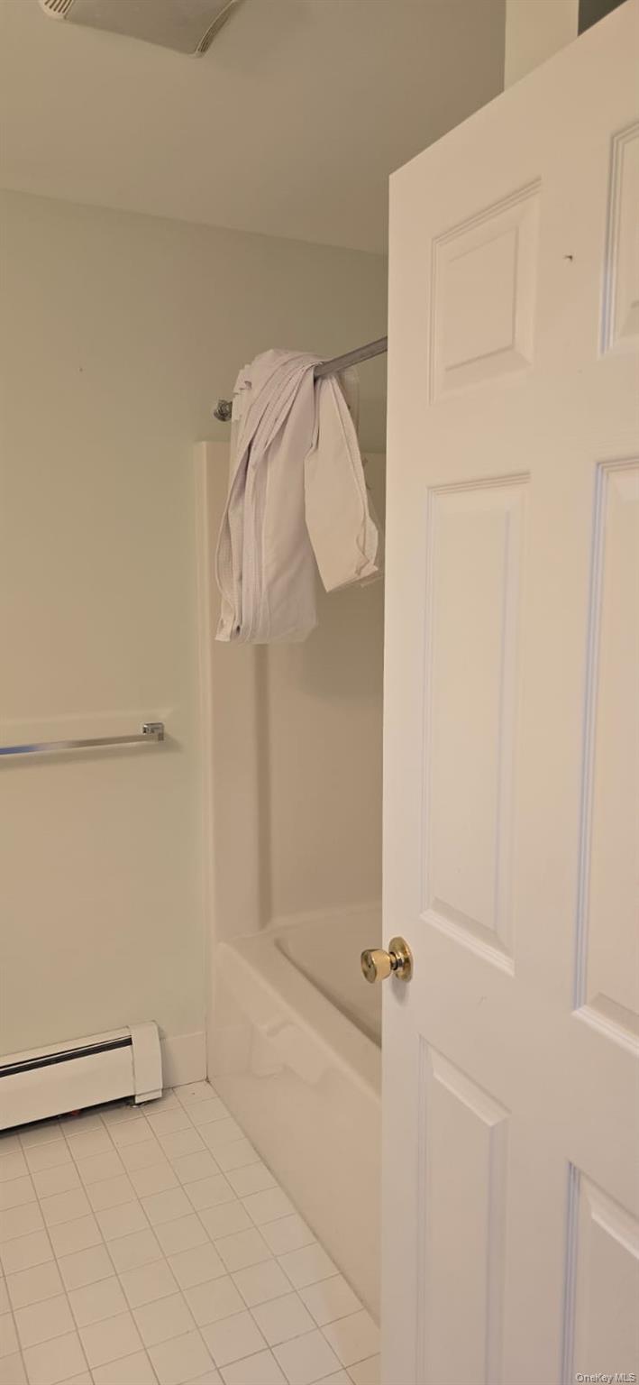 235 MacDougal Street Brooklyn, NY 11233 - Photo 19 of 21 Bathroom featuring baseboard heating, light tile patterned floors, a tub, and a shower