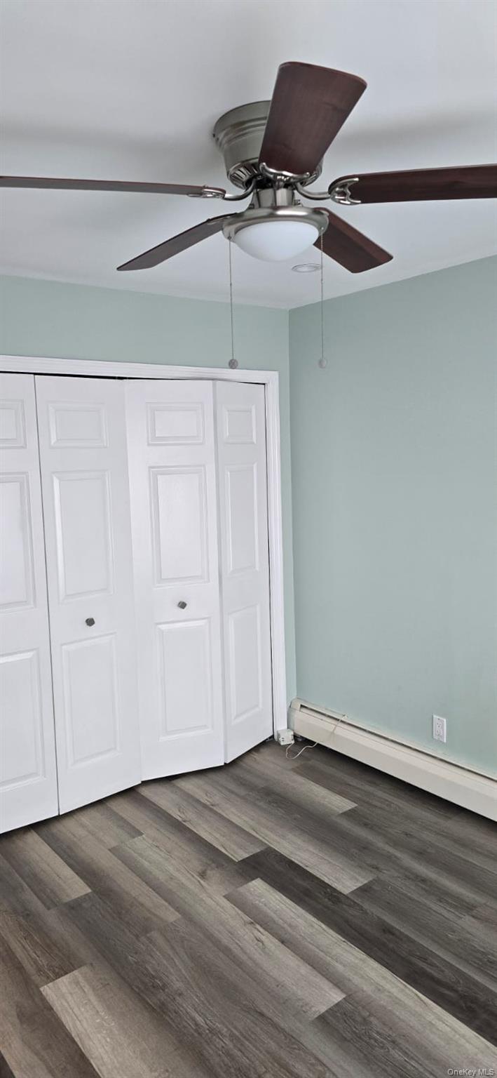 235 MacDougal Street Brooklyn, NY 11233 - Photo 3 of 21 Unfurnished bedroom with baseboard heating, dark wood-style floors, ceiling fan, and a closet