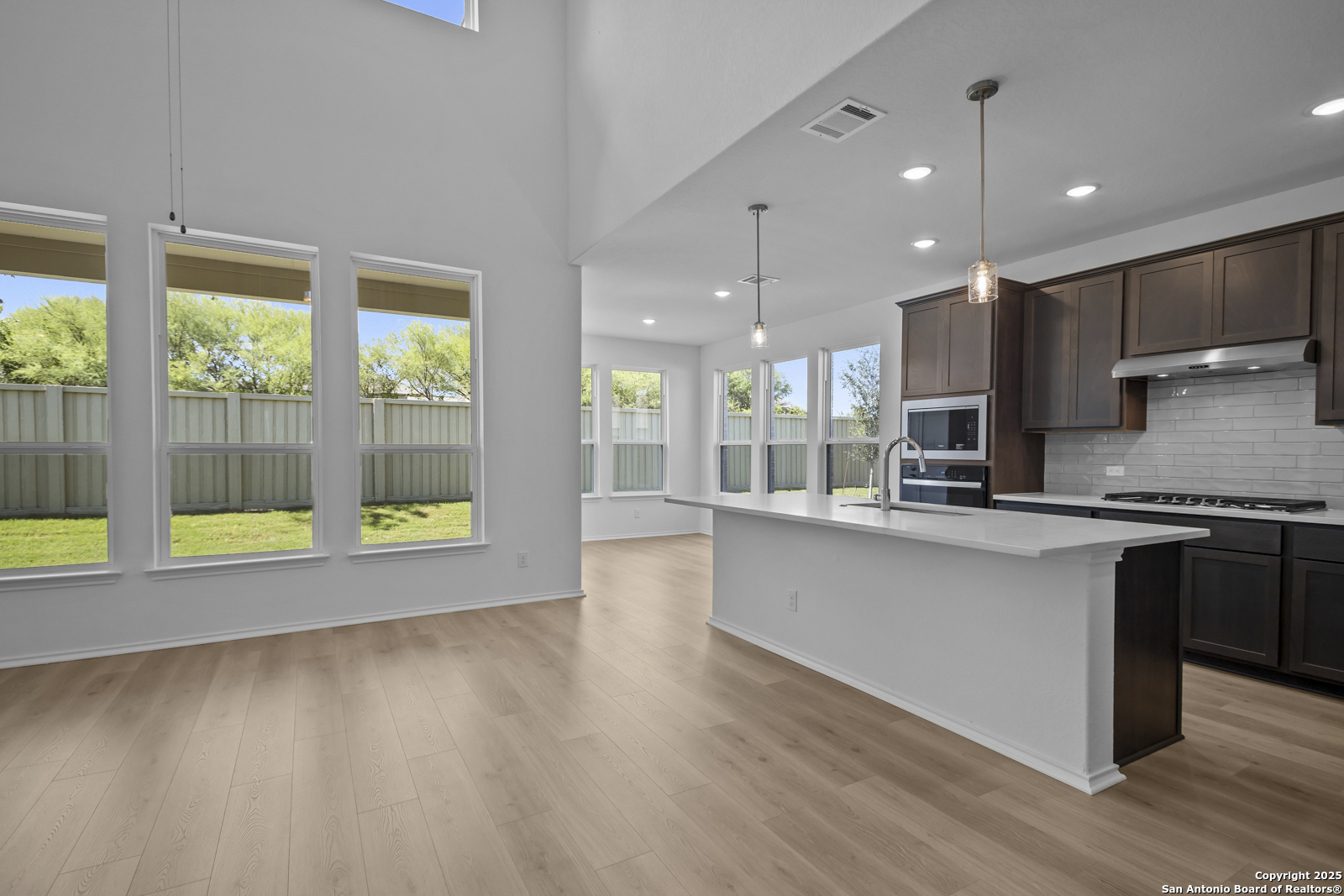 517 Foxtail Canyon Cibolo, TX 78108 - Photo 7 of 38 a large kitchen with stainless steel appliances a large counter top a stove a chimney a sink and a large window