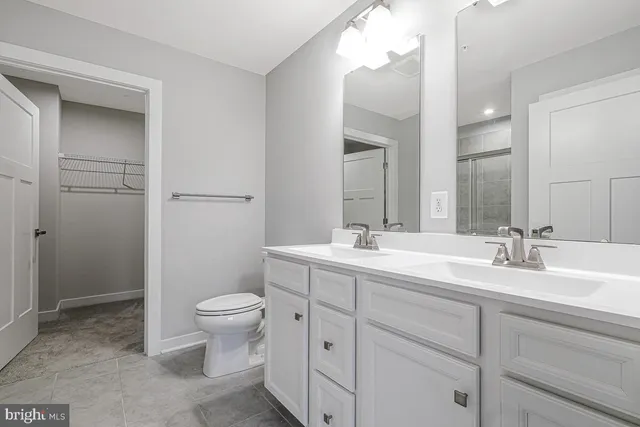 a bathroom with a double vanity sink toilet and a mirror