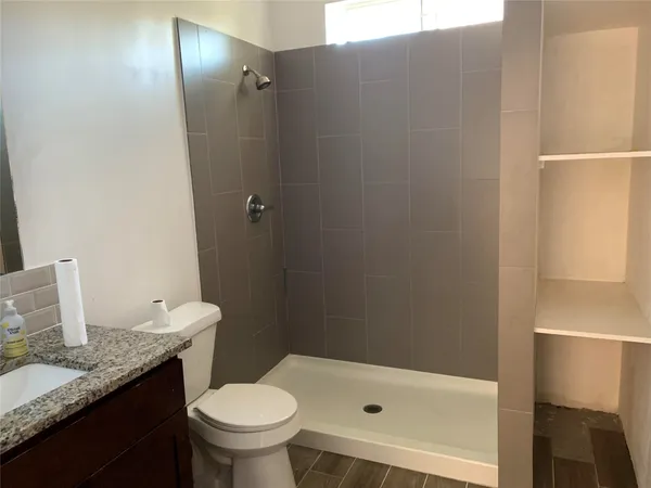 a bathroom with a granite countertop sink toilet and shower