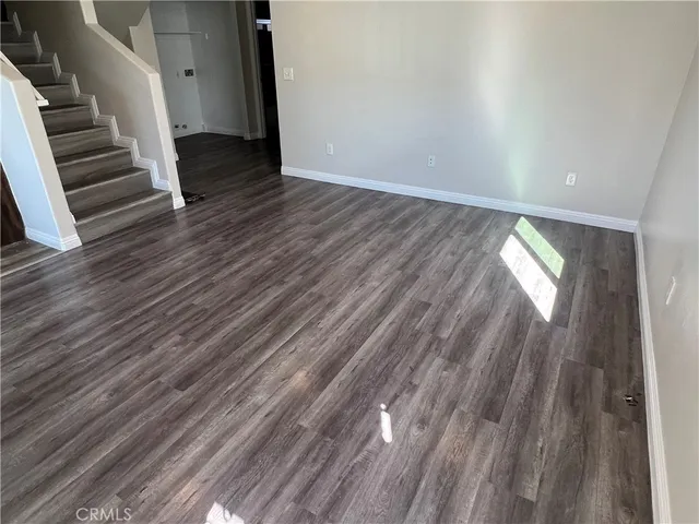 a view of an empty room with wooden floor and stairs