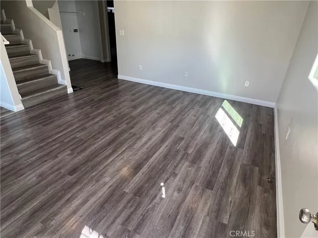 a view of an empty room with wooden floor and stairs