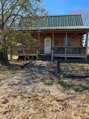a view of a small house with yard and wooden fence