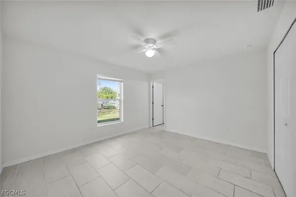 an empty room with windows and fan