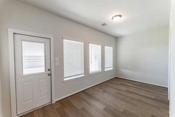 an empty room with wooden floor and windows