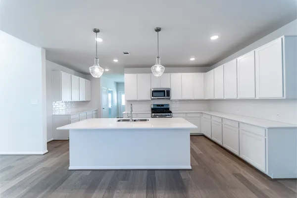 a large kitchen with kitchen island a stove a sink a center island and wooden floor