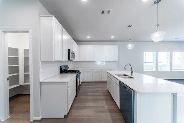 a kitchen with white cabinets appliances and a sink