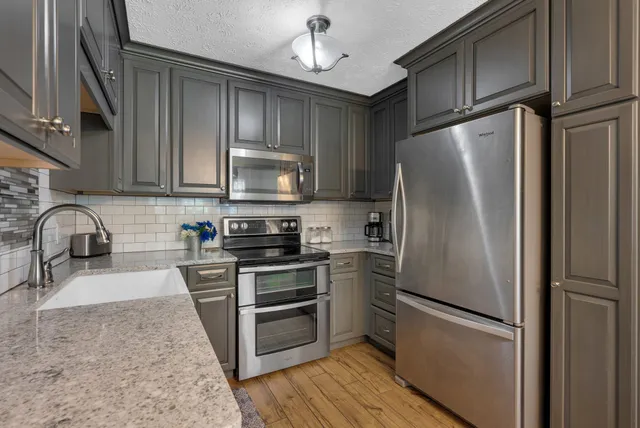 a kitchen with stainless steel appliances granite countertop a refrigerator stove and sink