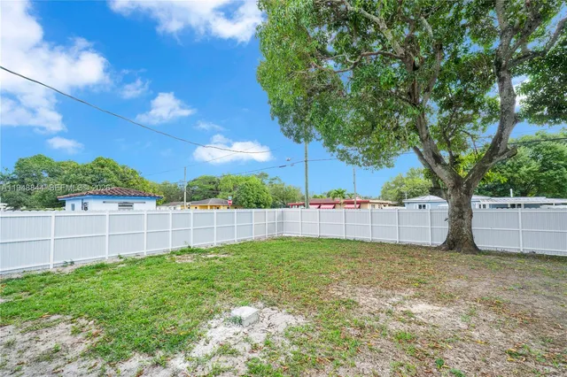 a view of a backyard with a tree and a wooden fence
