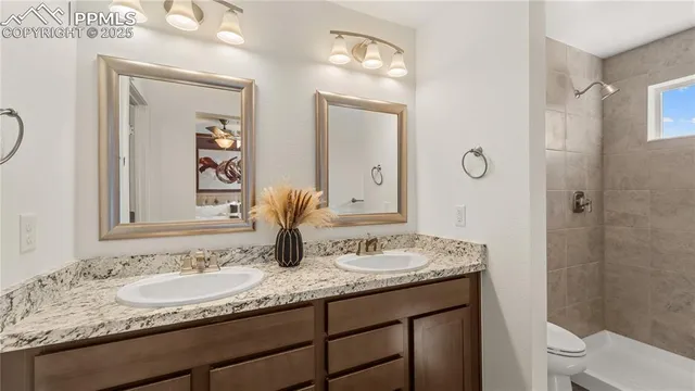 a bathroom with a granite countertop sink a toilet and a mirror