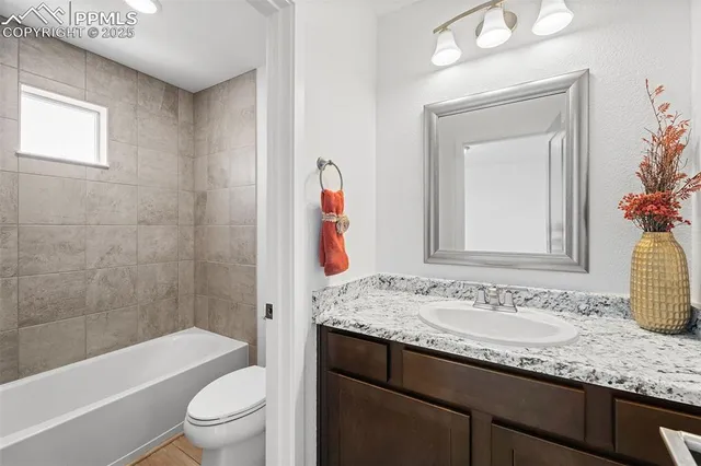 a bathroom with a granite countertop sink a toilet and shower