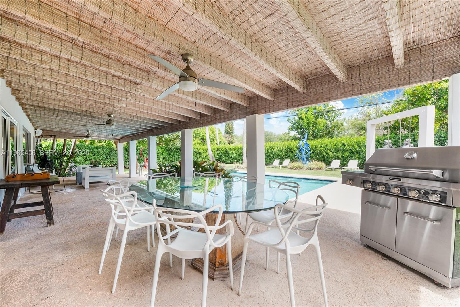 7401 Southwest 117th Street Pinecrest, FL 33156 - Photo 17 of 21 a view of a patio with table and chairs under an umbrella with a large tree