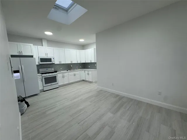 a view of kitchen with wooden floor electronic appliances and window