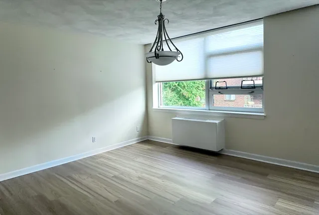 a room with wooden floor a ceiling fan and windows