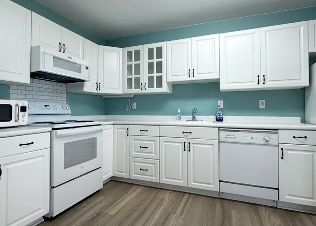 a kitchen with white cabinets and white appliances