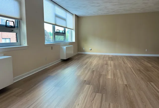 an empty room with wooden floor and windows