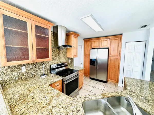 a kitchen with granite countertop a sink and a refrigerator