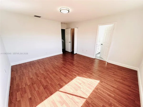 a view of empty room with wooden floor