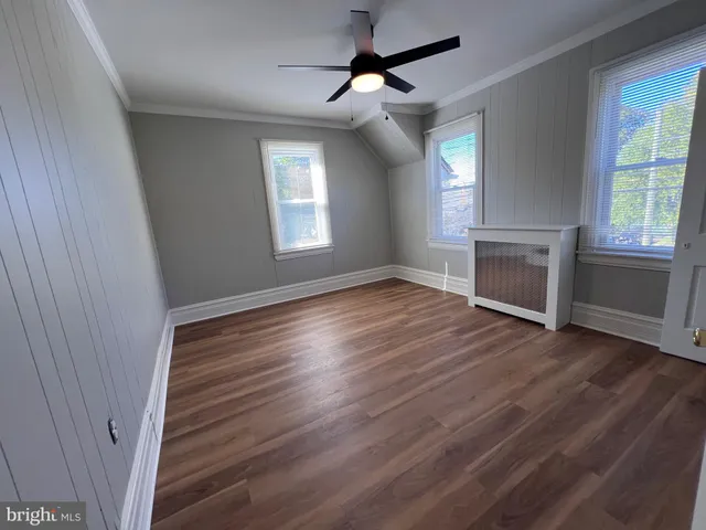 an empty room with wooden floor fireplace and windows