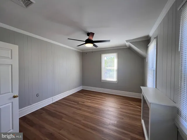 a view of empty room with wooden floor and fan