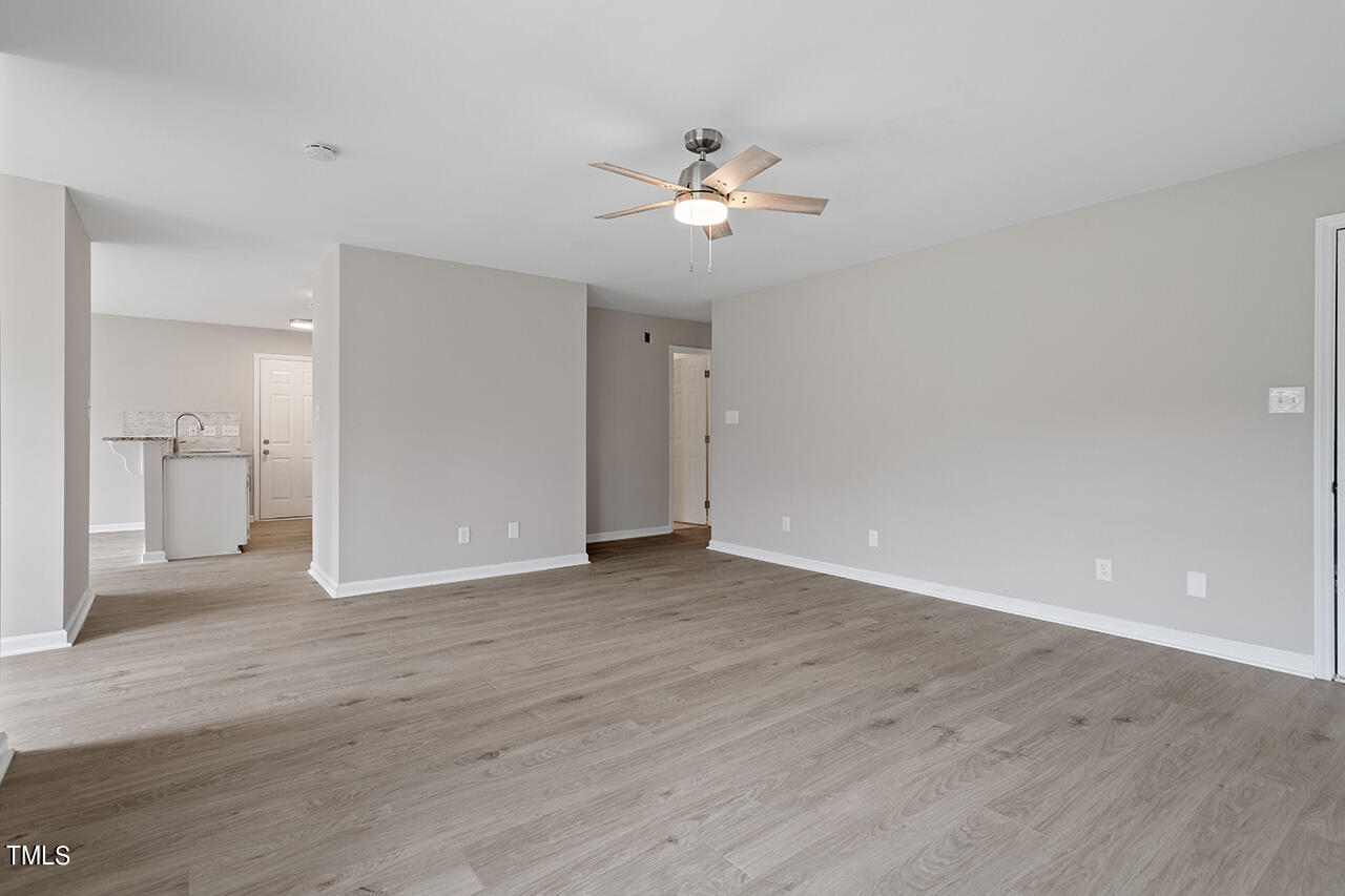 2127 Bainbridge Road Stedman, NC 28391 - Photo 11 of 27 a view of an empty room with wooden floor and a ceiling fan