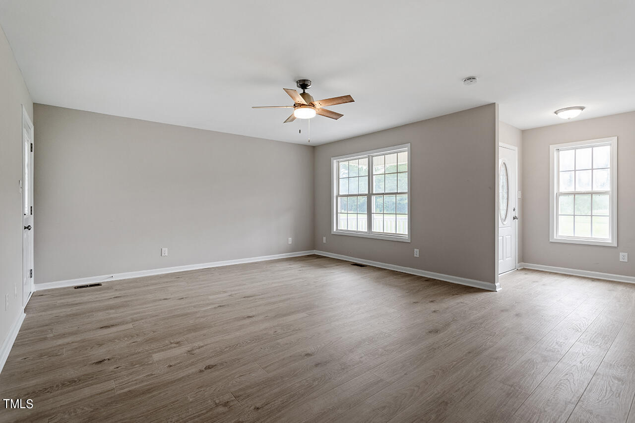 2127 Bainbridge Road Stedman, NC 28391 - Photo 13 of 27 an empty room with wooden floor ceiling fan and windows