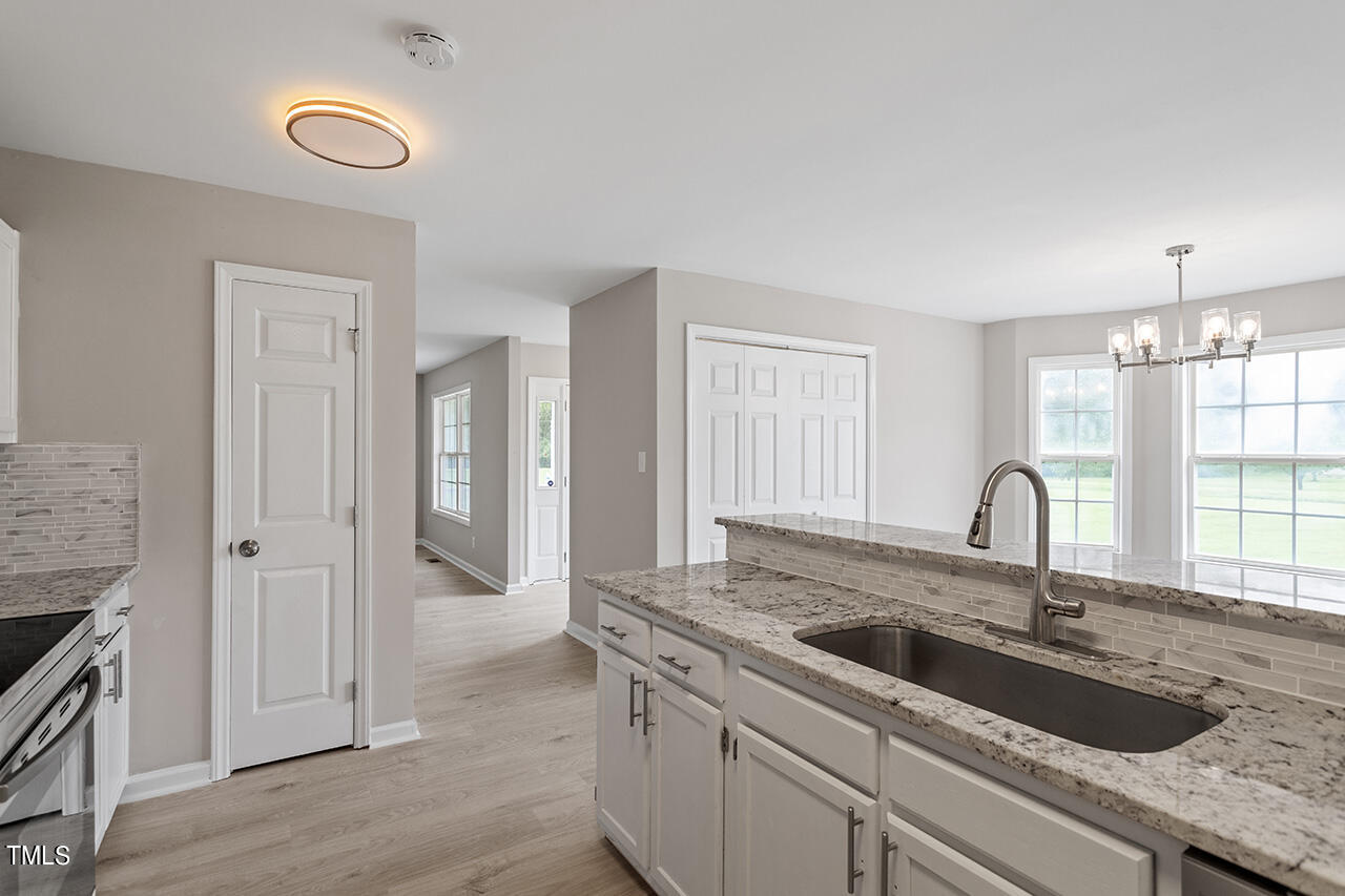 2127 Bainbridge Road Stedman, NC 28391 - Photo 5 of 27 a kitchen with granite countertop a sink and a stove top oven with wooden floor