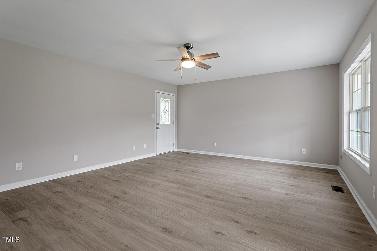 2127 Bainbridge Road Stedman, NC 28391 - Photo 10 of 27 an empty room with wooden floor ceiling fan and windows