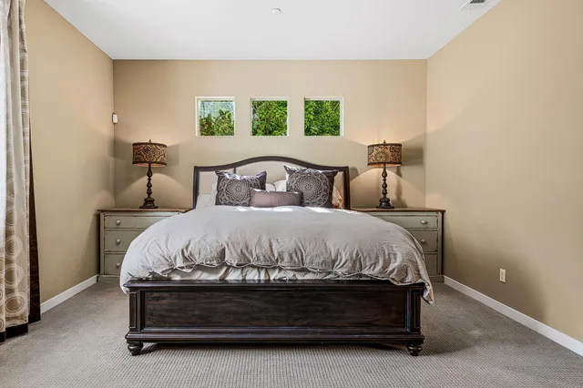 a bed sitting in a bedroom next to a window with a lamp