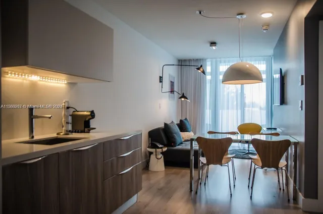a kitchen with granite countertop a dining table chairs and a refrigerator