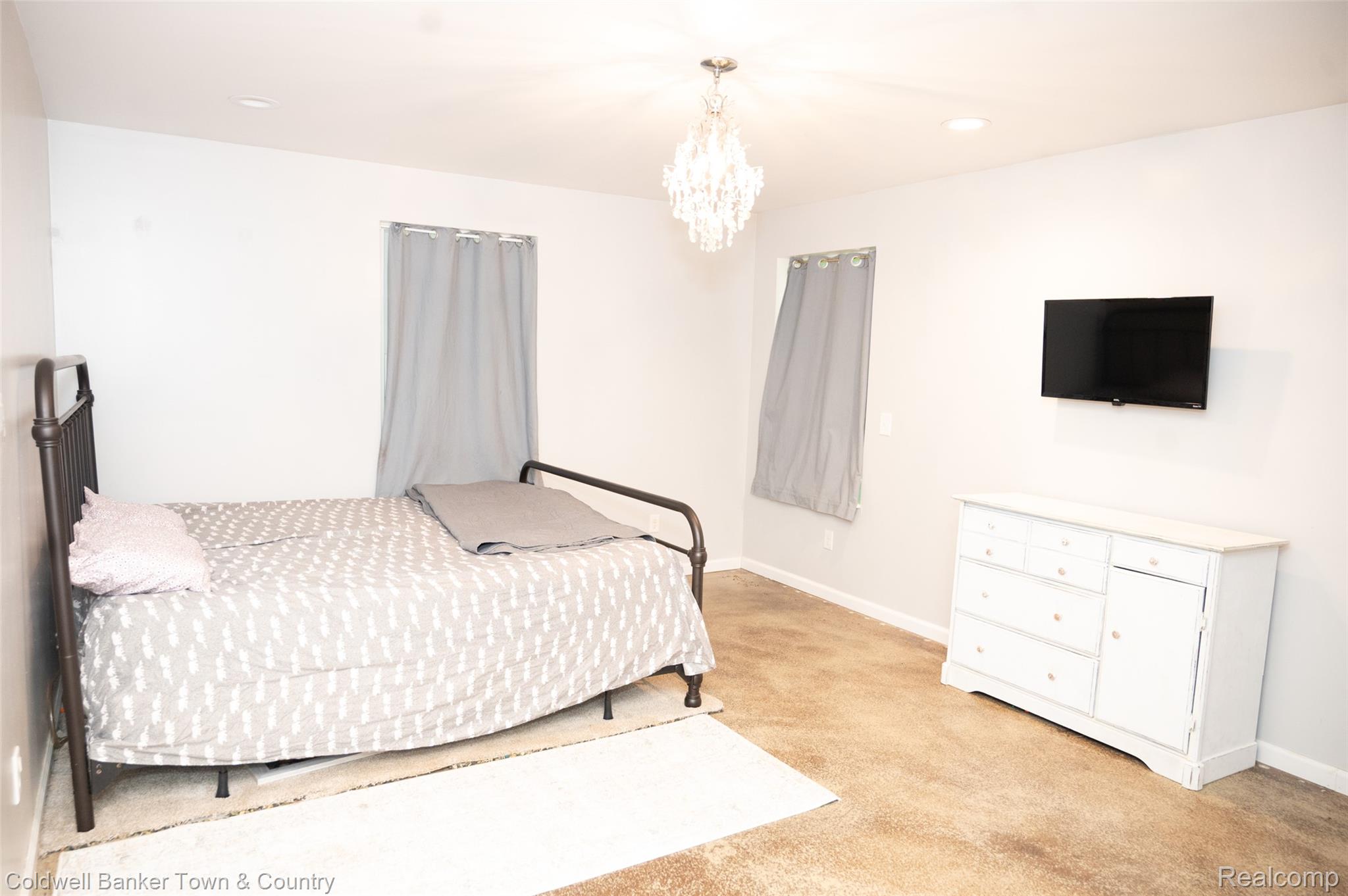 6150 North Fleming Road Howell, MI 48855 - Photo 14 of 23 Spacious room featuring neutral carpeting, recessed lighting, and a prominent crystal chandelier