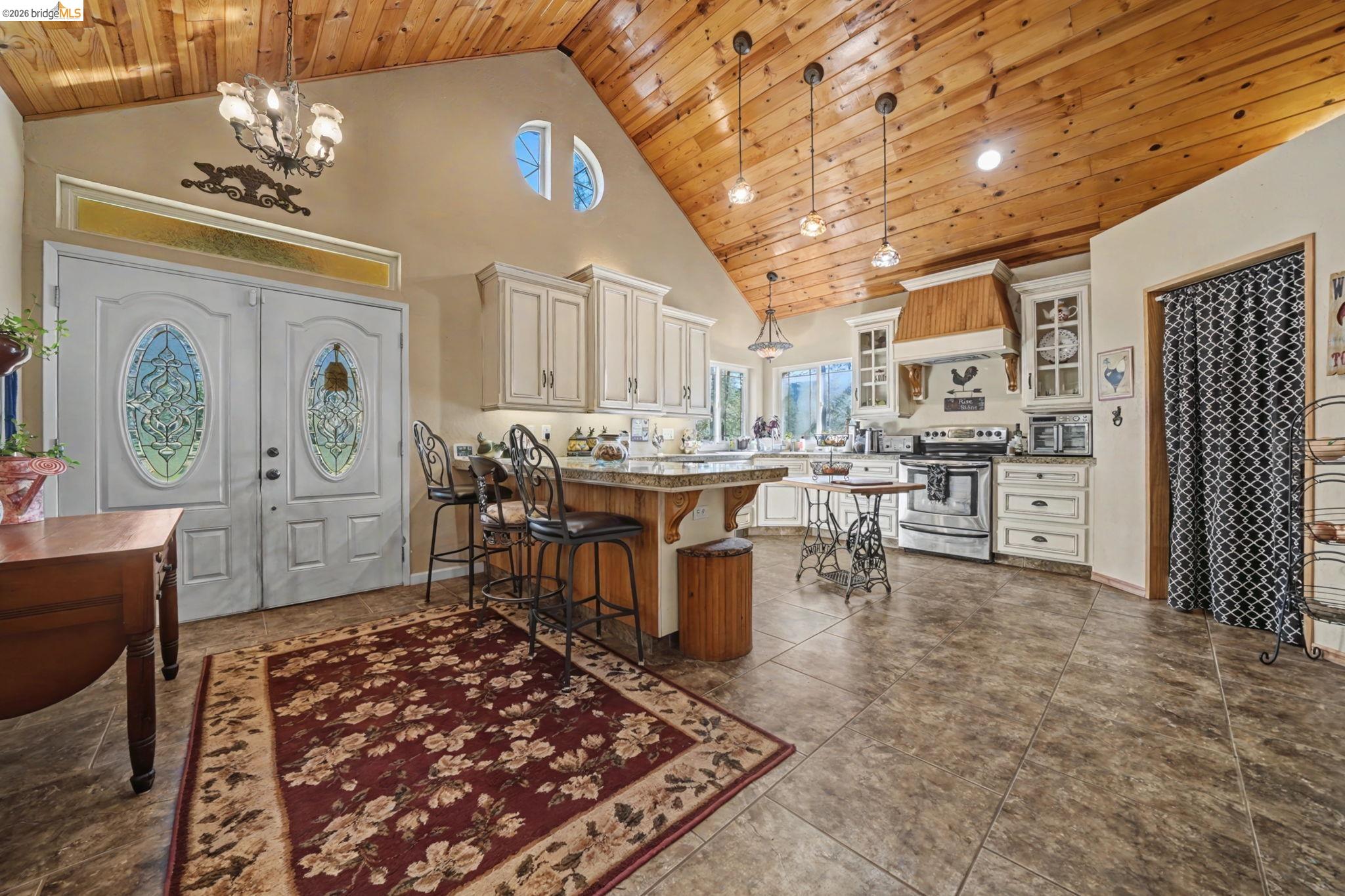 6145 Swiss Ranch Road Mountain Ranch, CA 95246 - Photo 12 of 60 Kitchen featuring a vaulted wooden ceiling, a breakfast bar area, electric stove, glass fronted cabinets, and suspended lighting