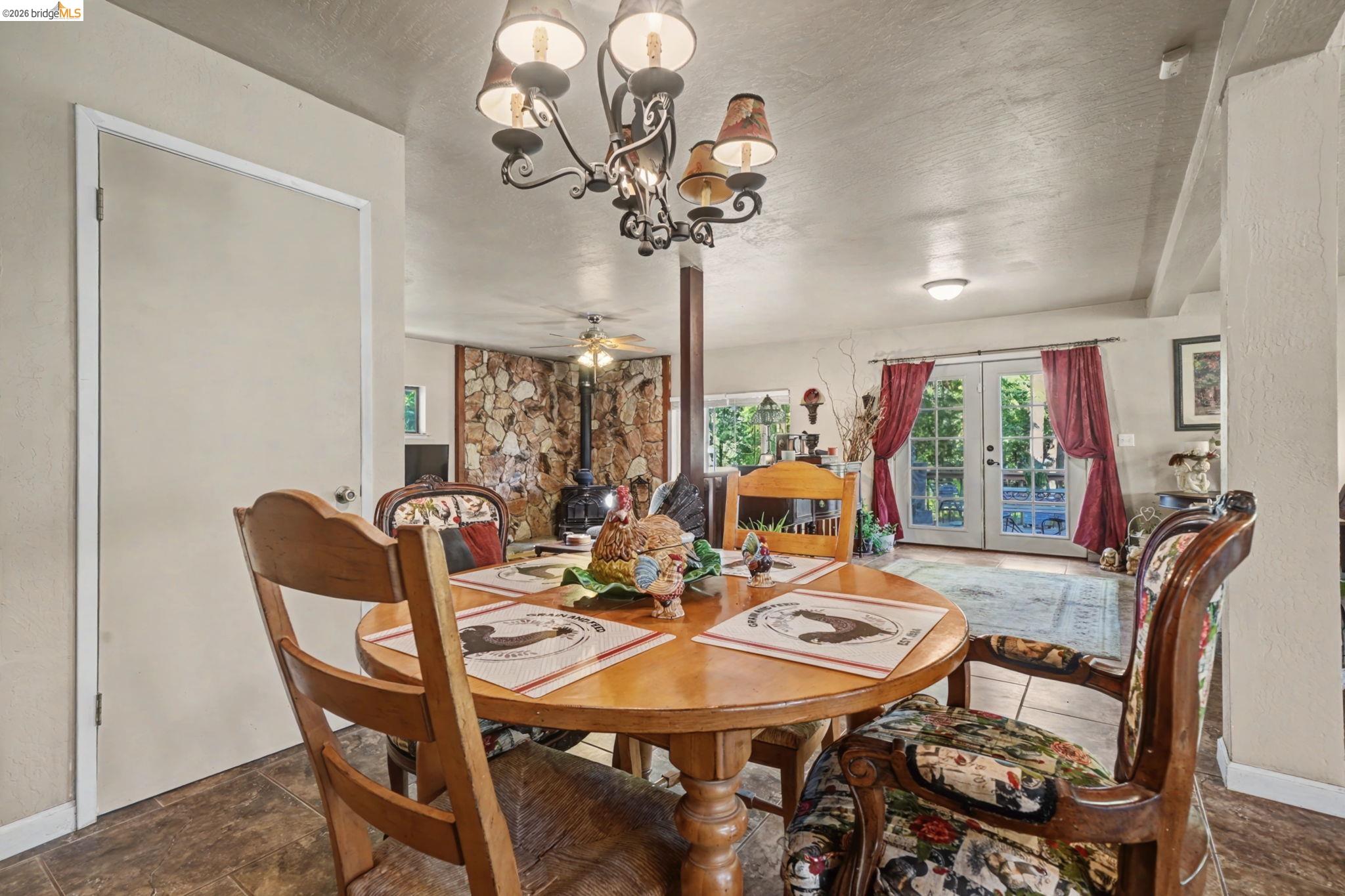 6145 Swiss Ranch Road Mountain Ranch, CA 95246 - Photo 25 of 60 Dining area featuring ceiling fan, french doors, a chandelier, and stone finish floors