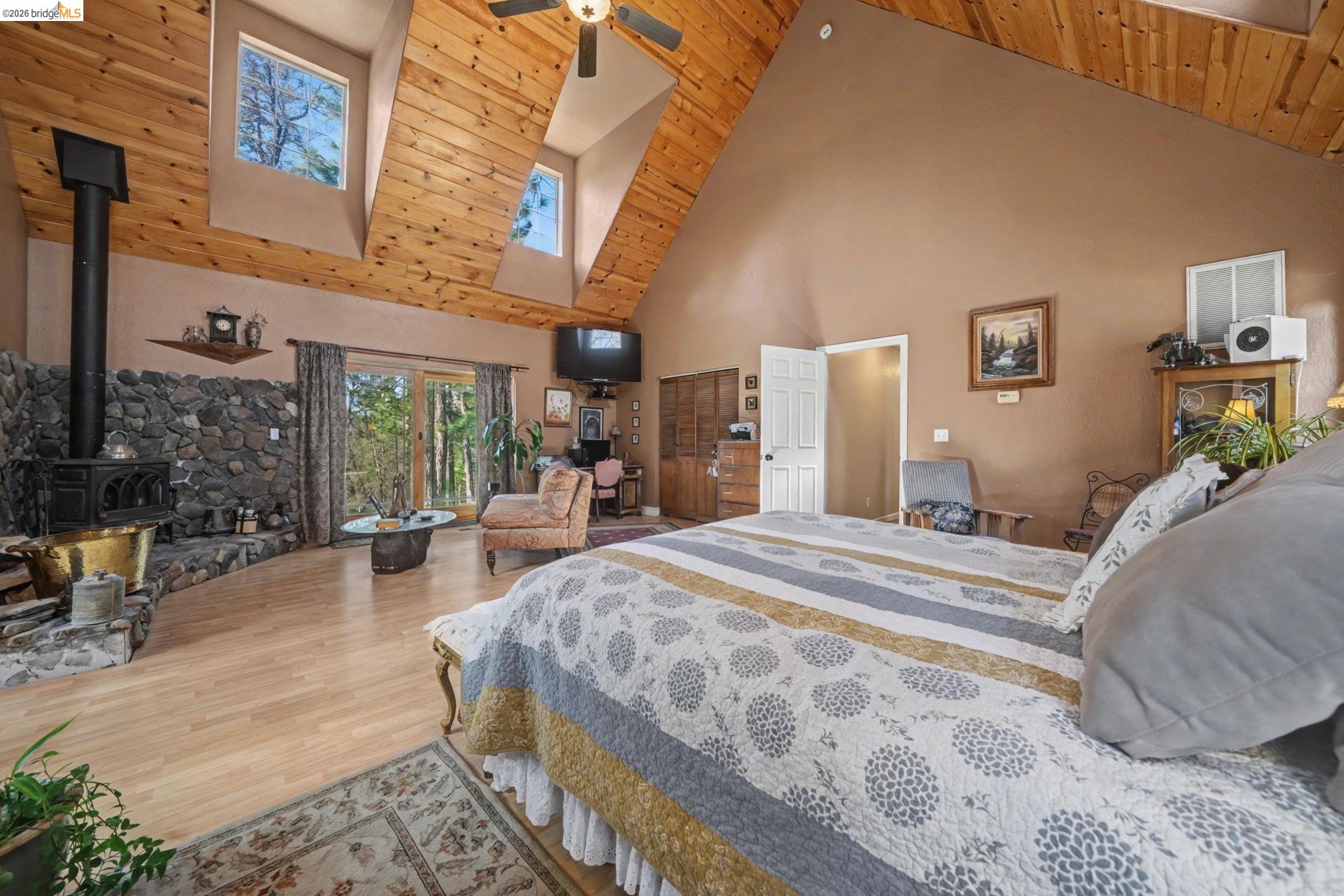 6145 Swiss Ranch Road Mountain Ranch, CA 95246 - Photo 35 of 60 Bedroom with a wood stove, wood finished floors, a high wood ceiling, ceiling fan, and access to exterior