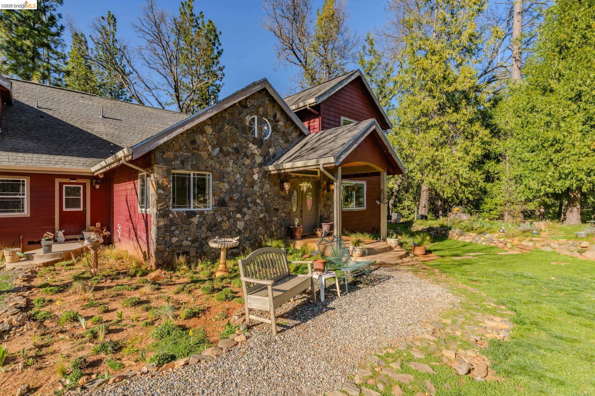 6145 Swiss Ranch Road Mountain Ranch, CA 95246 - Photo 8 of 60 Rustic home featuring a patio, stone siding, a front lawn, and a shingled roof