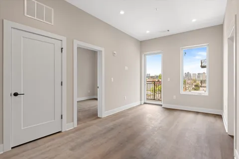 an empty room with wooden floor and windows