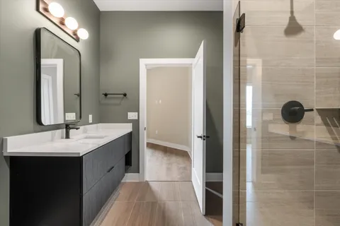a bathroom with a double vanity sink a mirror and shower