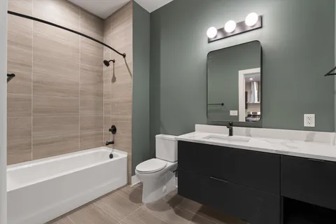 a bathroom with a bathtub shower sink vanity and toilet