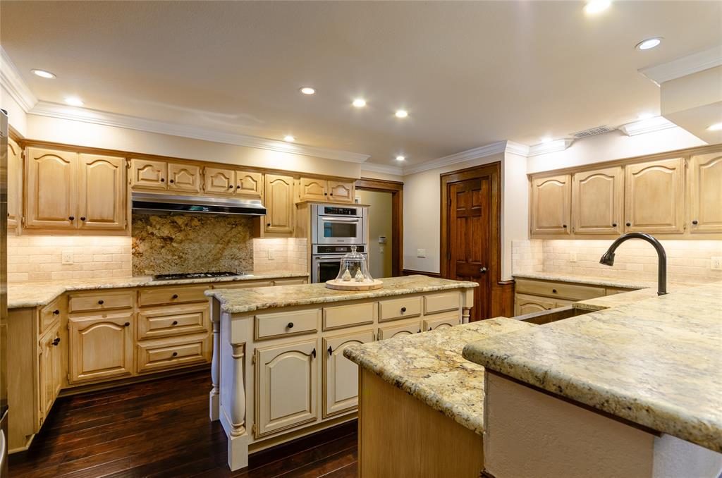 2605 Rothland Lane Plano, TX 75023 - Photo 10 of 40 a kitchen with stainless steel appliances granite countertop a sink and white cabinets with wooden floor