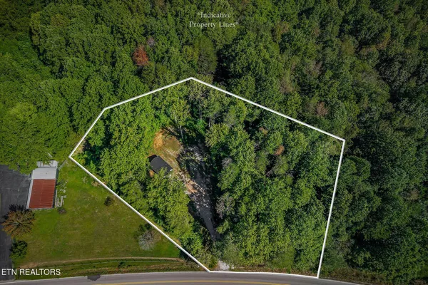 an aerial view of residential house with outdoor space and trees all around