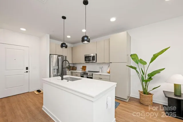 a kitchen with granite countertop a sink appliances and wooden floor