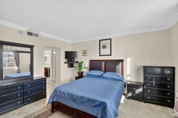 a bedroom with a bed and a large mirror on dresser