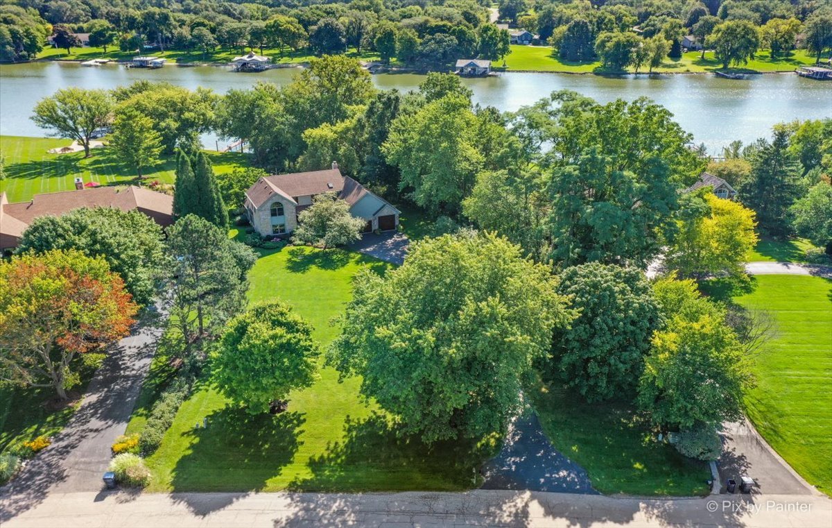 an aerial view of a house with a yard and lake view