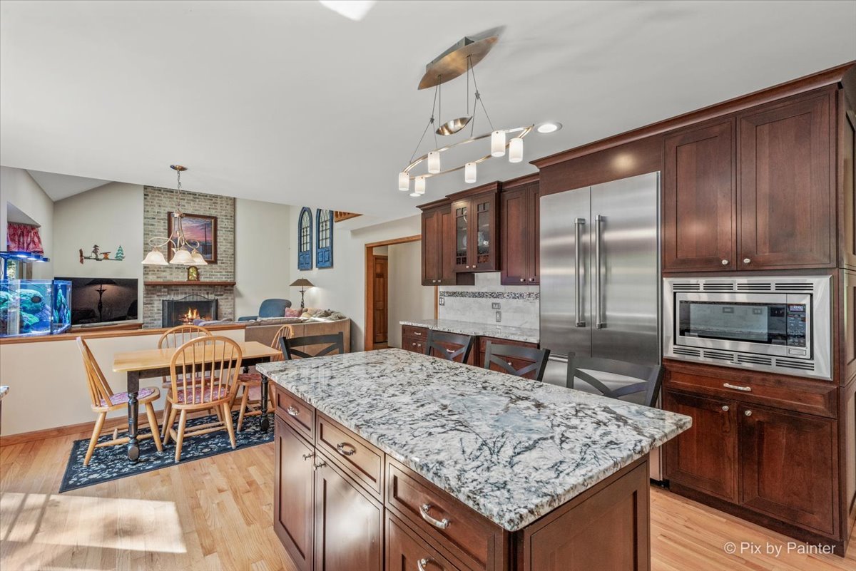 28683 Rivers Edge Drive Cary, IL 60013 - Photo 10 of 31 a kitchen with stainless steel appliances granite countertop a stove top oven a sink dishwasher a dining table and chairs with wooden floor