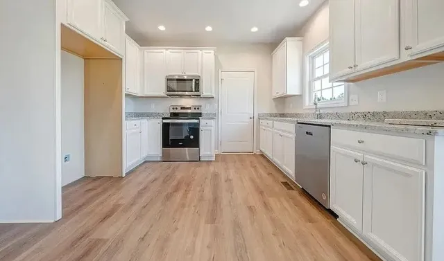 a kitchen with stainless steel appliances granite countertop a stove top oven a sink dishwasher and a refrigerator with wooden floor